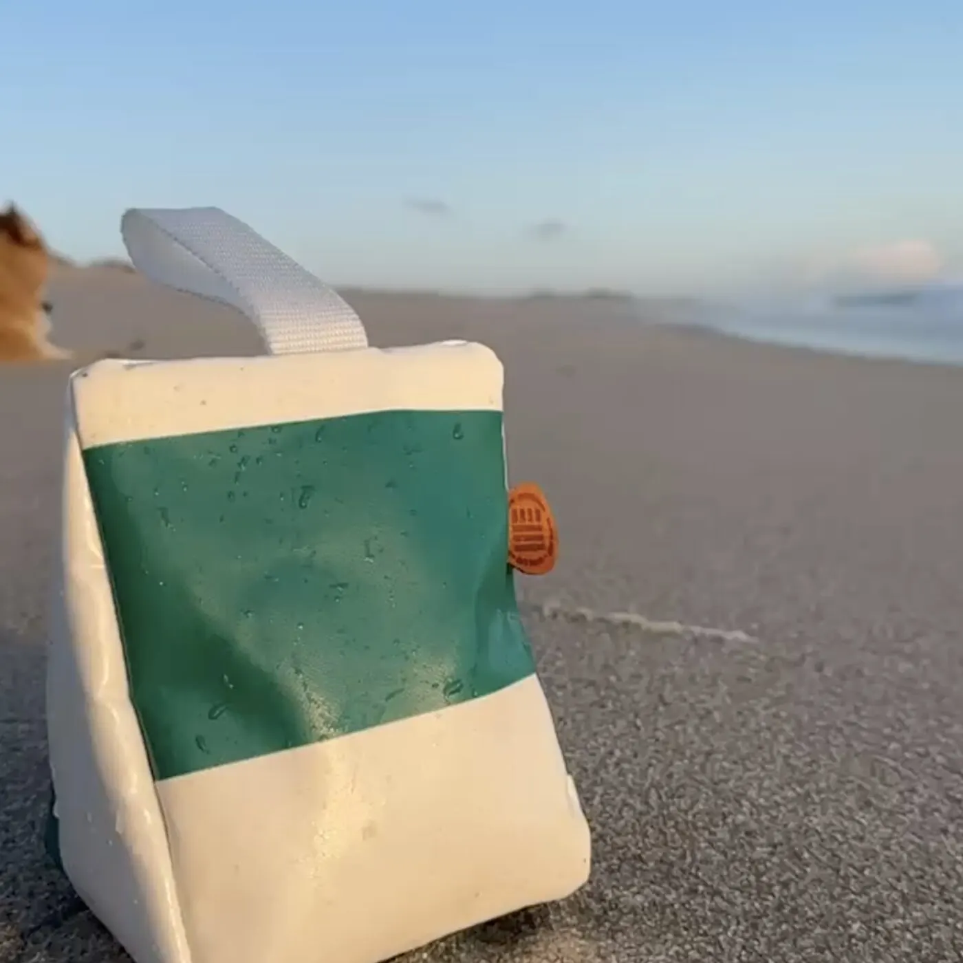 STURManker Türstopper Wattgrün-Weiß aus Sylter Strandkorb-Bezug am Sandstrand mit auflaufender Welle — STURMFREI Upcycling